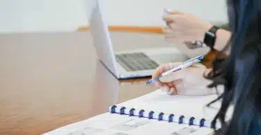 person holding pen writing on paper
