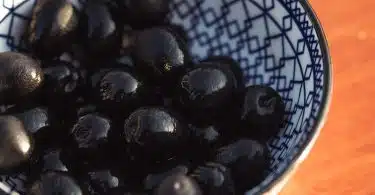 black round fruits on white and blue ceramic bowl